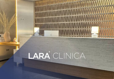 Mostrador de recepción moderno y luminoso con el logotipo de Clínica Lara, destacando un diseño elegante con paredes texturizadas y luz cálida.